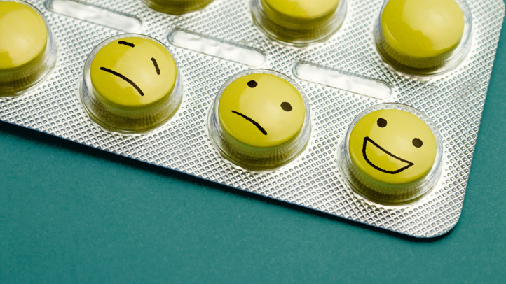 Yellow pills with different smiley faces in a blister pack