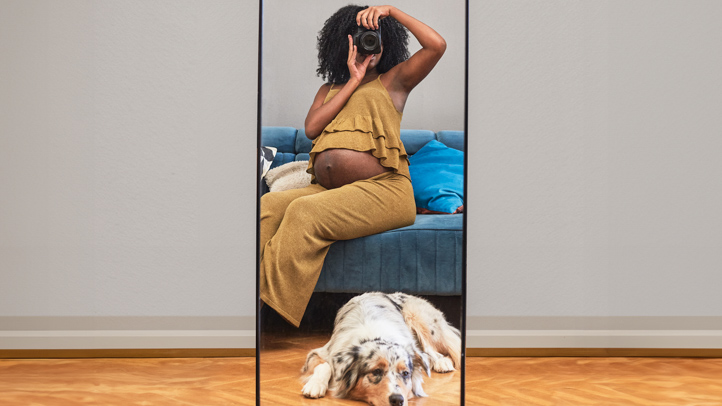 pregnant woman taking a selfie in a mirror with a camera