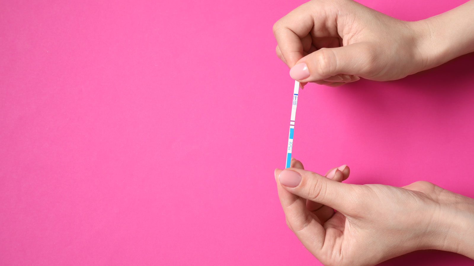 Woman holding pregnancy test on pink background